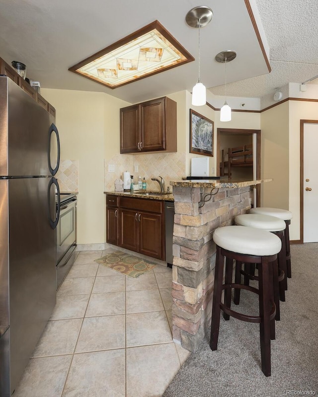 kitchen featuring backsplash, a breakfast bar area, a peninsula, stainless steel appliances, and a sink