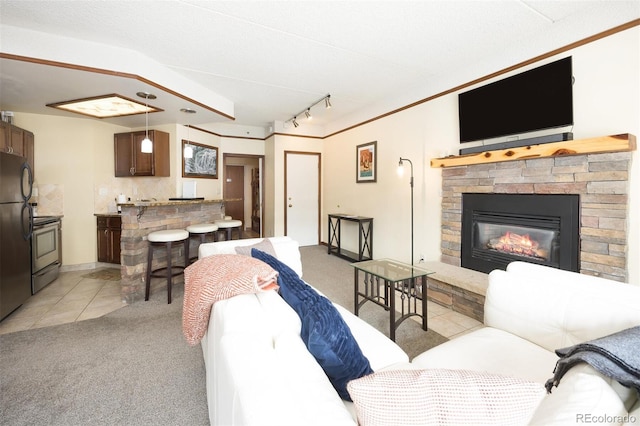 living room featuring a stone fireplace, track lighting, light tile patterned flooring, and light carpet