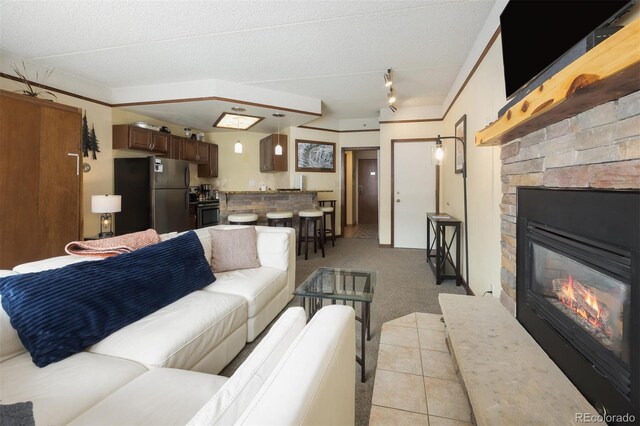 living room with a stone fireplace, light tile patterned floors, and light carpet