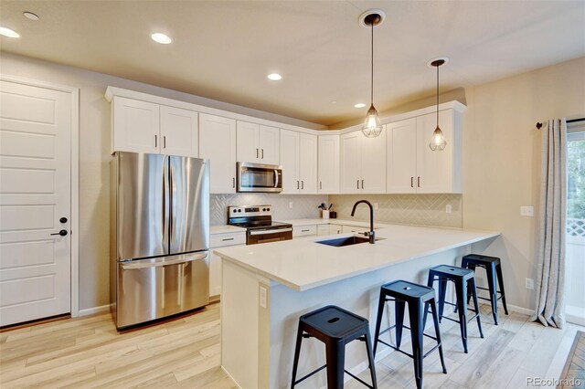 3765 W 88th Ct, Westminster, CO 80031 - kitchen featuring stainless steel appliances, a sink, light wood-style floors, a kitchen breakfast bar, and a peninsula