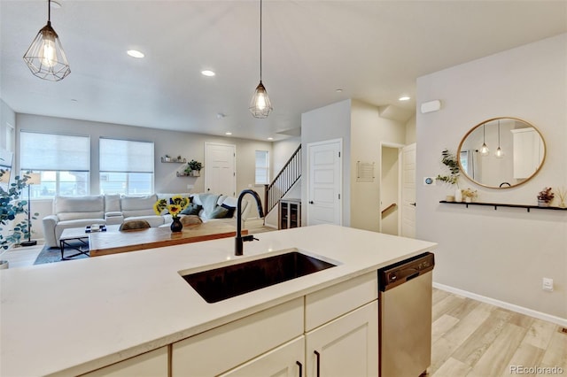 3765 W 88th Ct, Westminster, CO 80031 - kitchen with stainless steel dishwasher, a sink, open floor plan, pendant lighting, and light wood-style floors