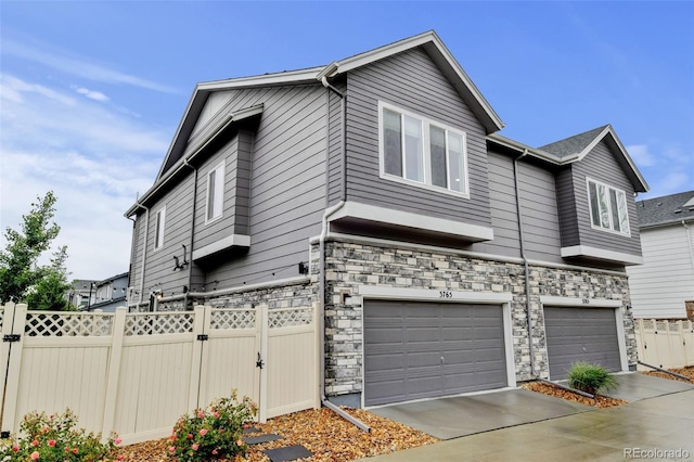 3765 W 88th Ct, Westminster, CO 80031 - view of front facade with a garage, stone siding, concrete driveway, and a gate