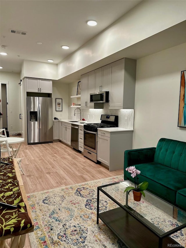 2876 W 53rd Ave Unit 305, Denver, CO 80221 - kitchen featuring appliances with stainless steel finishes, a sink, light wood-style floors, light countertops, and open shelves