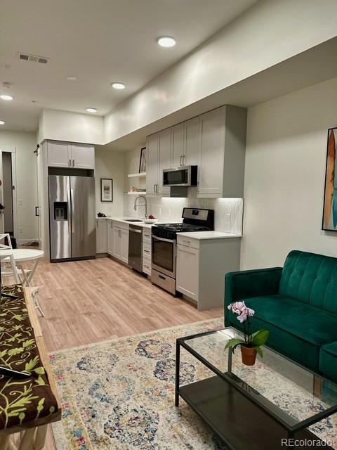2876 W 53rd Ave Unit 305, Denver, CO 80221 - kitchen with appliances with stainless steel finishes, a sink, light wood finished floors, light countertops, and backsplash
