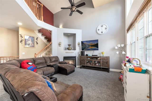 carpeted living room with a towering ceiling, plenty of natural light, and ceiling fan