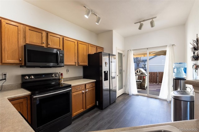 kitchen with brown cabinets, light countertops, stainless steel fridge, and electric range