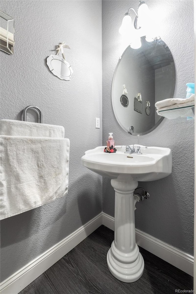 bathroom featuring baseboards, wood finished floors, and a textured wall