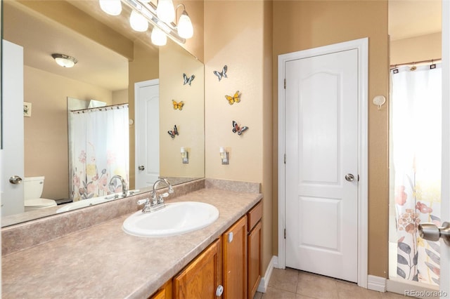 bathroom featuring baseboards, vanity, toilet, and tile patterned floors