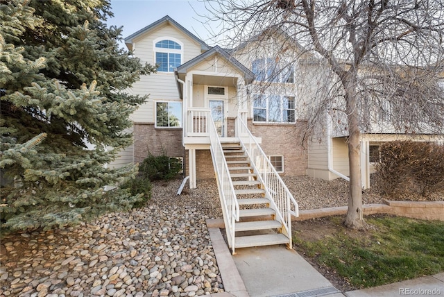 view of front of property with stairs and brick siding