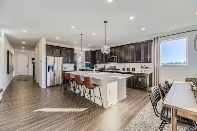 kitchen featuring a breakfast bar area, dark brown cabinets, light wood-type flooring, and appliances with stainless steel finishes