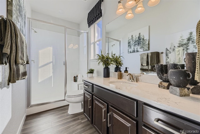 full bathroom featuring baseboards, toilet, a stall shower, wood finished floors, and vanity