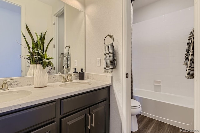 bathroom featuring a sink, toilet, wood finished floors, and double vanity