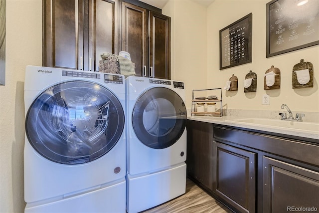 laundry room with a sink, cabinet space, light wood finished floors, and washer and dryer