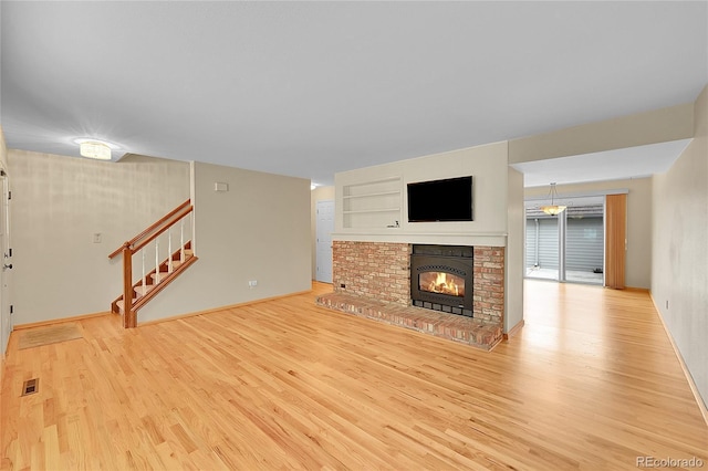 9930 W Progress Pl, Littleton, CO 80123 - unfurnished living room with wood finished floors, stairs, a fireplace, and baseboards