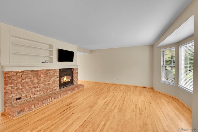 9930 W Progress Pl, Littleton, CO 80123 - unfurnished living room with wood finished floors, a brick fireplace, and built in features
