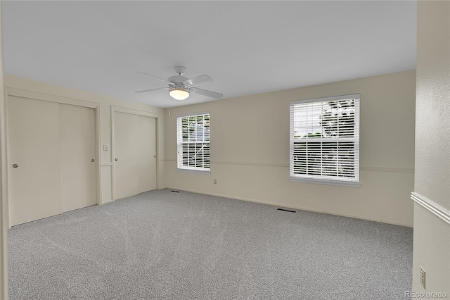 9930 W Progress Pl, Littleton, CO 80123 - unfurnished bedroom with two closets, multiple windows, carpet, and a ceiling fan