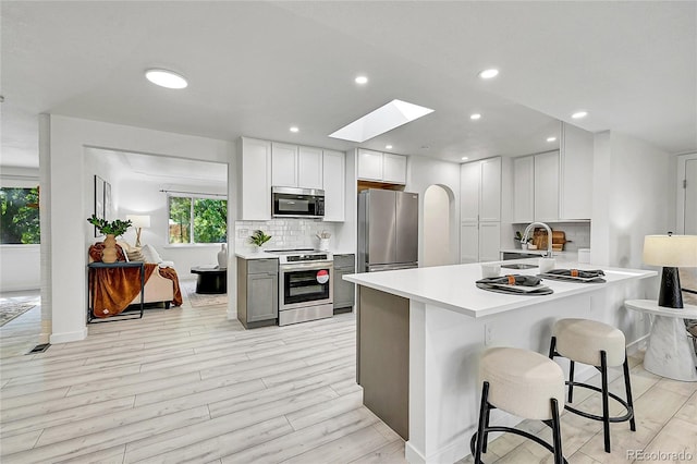 kitchen with tasteful backsplash, white cabinetry, a kitchen breakfast bar, kitchen peninsula, and stainless steel appliances