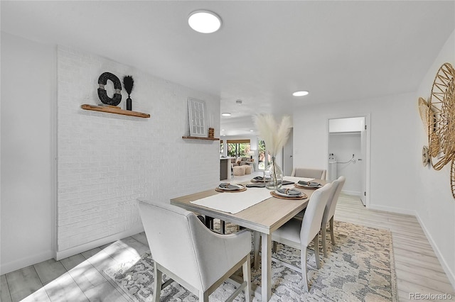 dining room with brick wall and light wood-type flooring