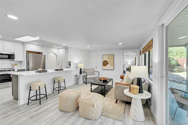 living room with light hardwood / wood-style floors and a skylight