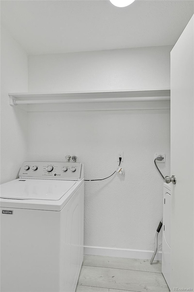 clothes washing area with washer / dryer and light hardwood / wood-style flooring