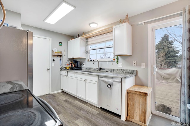 kitchen with sink, stainless steel appliances, white cabinets, and light wood-type flooring