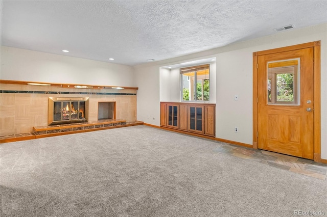 7681 S Jellison St, Littleton, CO 80127 - unfurnished living room with a fireplace, a textured ceiling, recessed lighting, carpet flooring, and stone finish floors