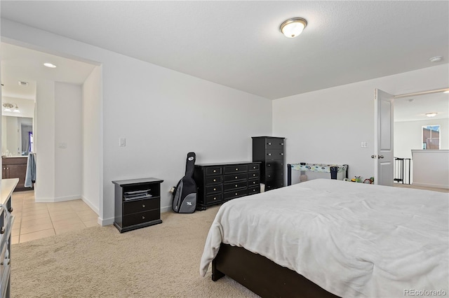 bedroom with ensuite bathroom and light colored carpet