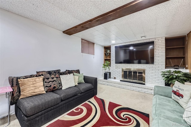 carpeted living room featuring beamed ceiling, a brick fireplace, and built in shelves