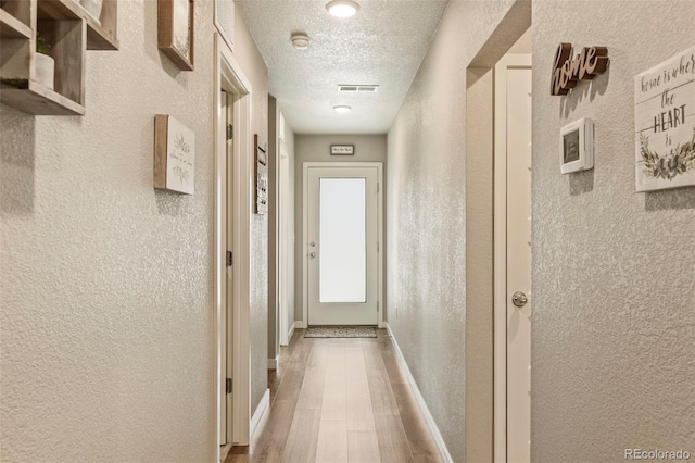 719 S Hoover Ave, Fort Lupton, CO 80621 - corridor featuring a textured wall, a textured ceiling, baseboards, and wood finished floors