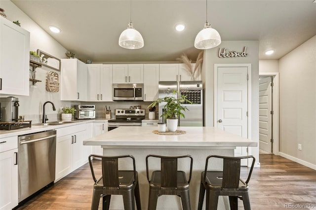 719 S Hoover Ave, Fort Lupton, CO 80621 - kitchen with appliances with stainless steel finishes, a sink, a breakfast bar area, white cabinetry, and recessed lighting