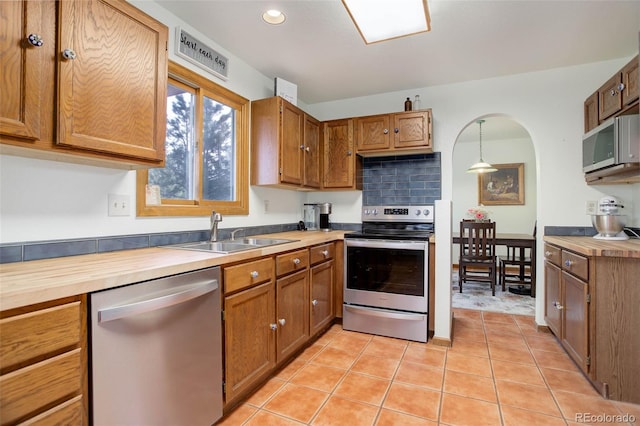 kitchen featuring pendant lighting, light tile patterned flooring, sink, and appliances with stainless steel finishes