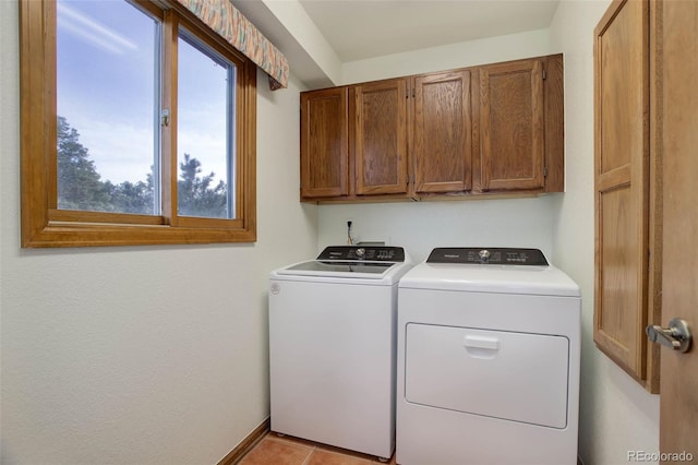 laundry room featuring cabinets, light tile patterned floors, and washing machine and dryer