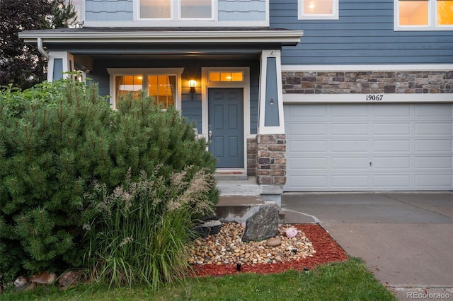 19067 W 57th Dr, Golden, CO 80403 - doorway to property with stone siding, driveway, and an attached garage