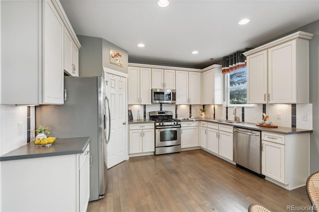 19067 W 57th Dr, Golden, CO 80403 - kitchen with stainless steel appliances, backsplash, hardwood / wood-style floors, dark countertops, and recessed lighting