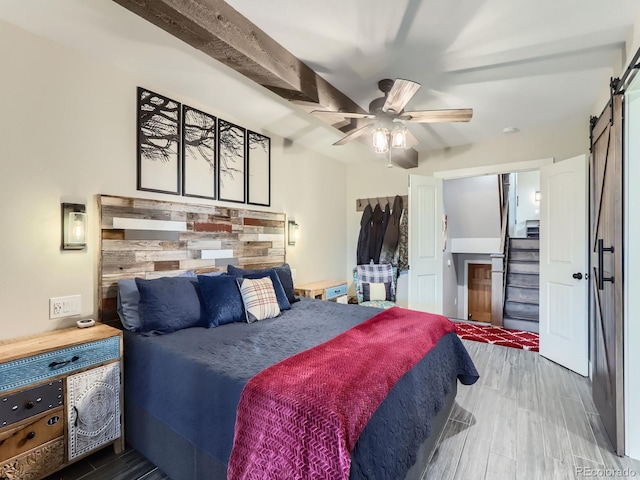 7273 Silverhorn Dr, Evergreen, CO 80439 - bedroom with a barn door, wood finished floors, and a ceiling fan