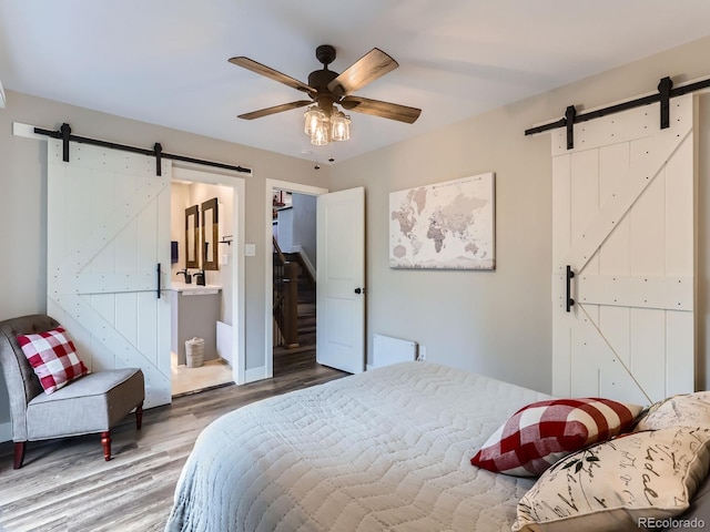 7273 Silverhorn Dr, Evergreen, CO 80439 - bedroom with a barn door, wood finished floors, ensuite bath, and ceiling fan