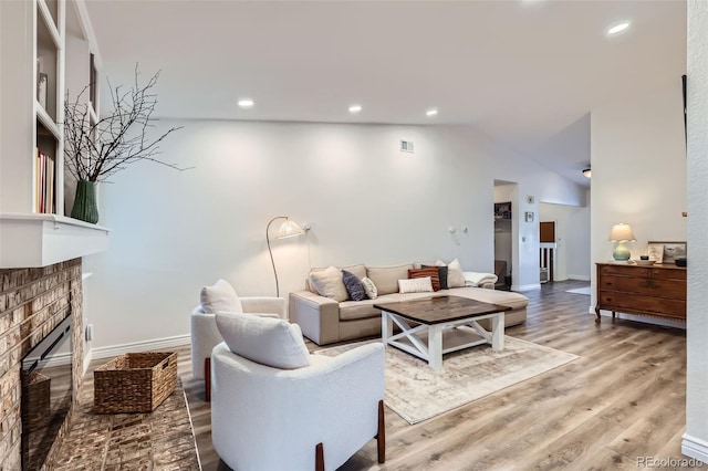 living room featuring hardwood / wood-style flooring, a fireplace, and vaulted ceiling