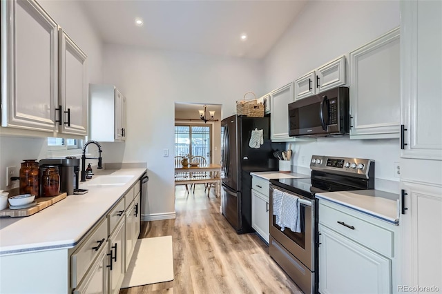 kitchen with appliances with stainless steel finishes, sink, a notable chandelier, and light wood-type flooring