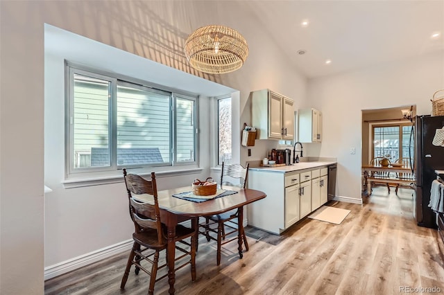 kitchen featuring sink, light wood-type flooring, a high ceiling, and black appliances