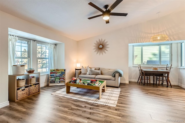 living room with dark wood-type flooring, vaulted ceiling, and ceiling fan