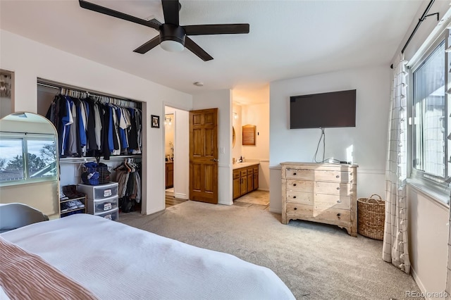 carpeted bedroom featuring ceiling fan, a closet, ensuite bathroom, and multiple windows