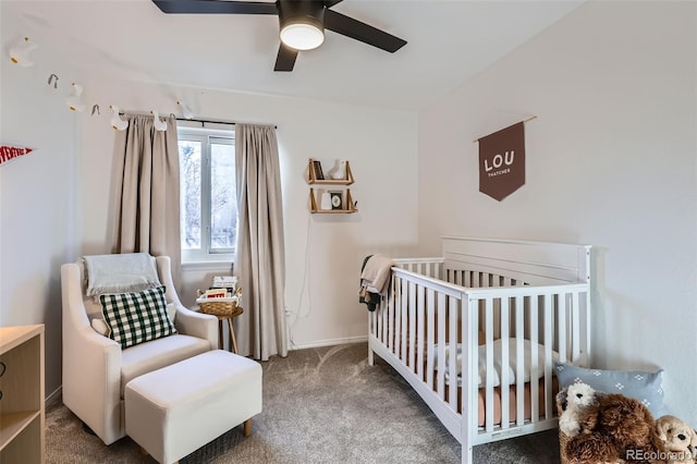 carpeted bedroom with a crib and ceiling fan