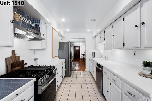 kitchen with a sink, light tile patterned floors, white cabinets, stainless steel appliances, and recessed lighting