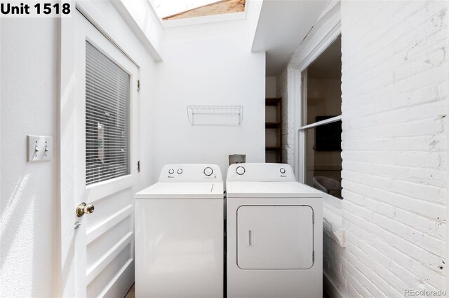 laundry room with washing machine and clothes dryer, laundry area, and a skylight