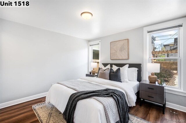 bedroom featuring baseboards, multiple windows, and wood finished floors