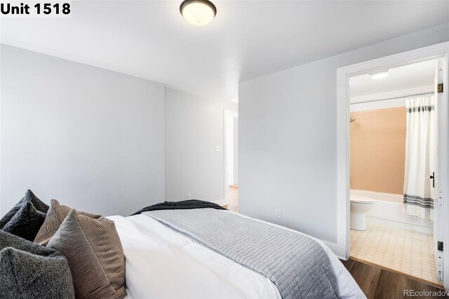 bedroom with baseboards, wood finished floors, and connected bathroom