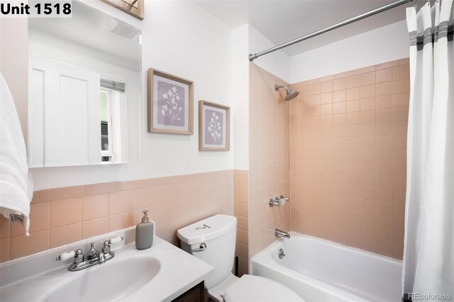 full bath with visible vents, tile walls, shower / bath combo, vanity, and toilet