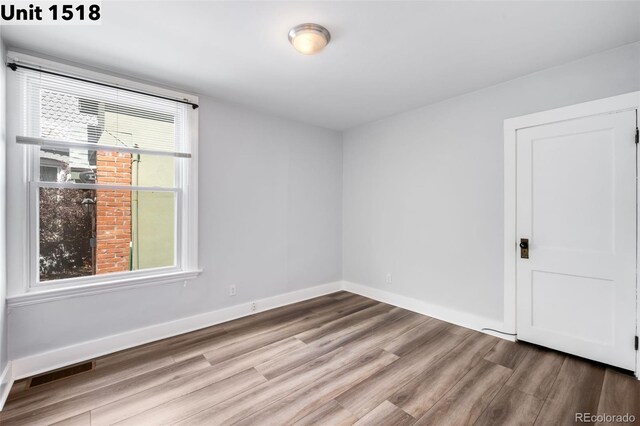 unfurnished room with baseboards, visible vents, and wood finished floors
