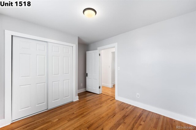 unfurnished bedroom featuring baseboards, light wood-style flooring, and a closet