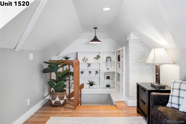 interior space with baseboards, wood finished floors, and lofted ceiling